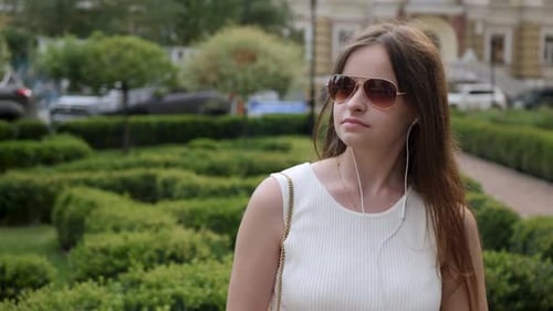 Woman puts on sunglasses in city park