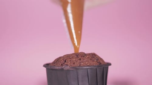 Chocolate Cupcake Being Frosted with Brown Icing
