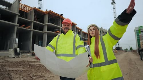 Female Construction Engineer and Aged Professional Foreman are Discussing Construction Plan in