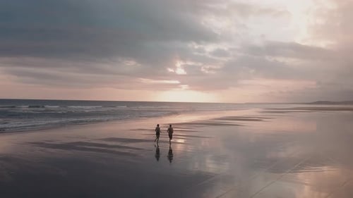 People Running on Reflective Beach at Sunrise