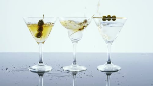 Three Cocktail Glasses being Filled with Golden Liquid