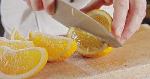 Nahaufnahme eines Kochmessers beim Schälen und Schneiden einer Orange