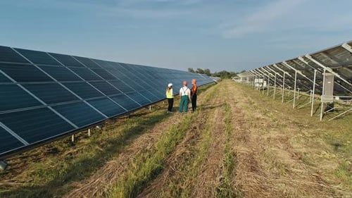 Three Employees of Alternative Power Plant Walking and Talking About Scheme of