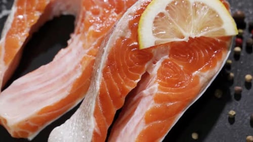 Lachs. Rotes Forellen-Fischsteak mit Kräutern und Zitrone und Olivenöl, rotiert auf Schiefer.
