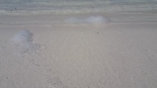 Luftaufnahme eines perfekten Strandabenteuers an der Küste durch blaugrünes Wasser mit weißem Sandhintergrund