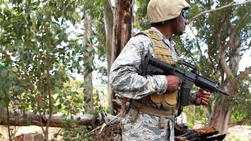 Soldier Standing Alertly in Wooded Area