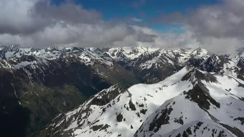 Air Flight Through Mountain Clouds Over Beautiful Snowcapped Peaks of Mountains and Glaciers