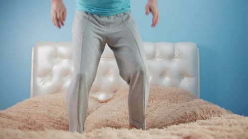Person Jumping on Bed in Bedroom