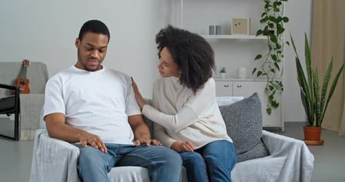 Woman Comforts Distressed Man on Couch at Home