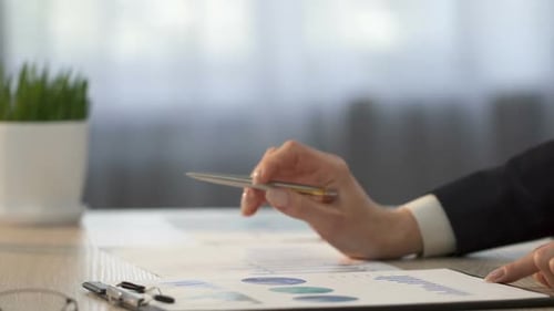 Analista financeiro comparando estatísticas da empresa e fazendo anotações em gráficos