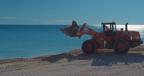 Carregadeira de construção funciona em uma costa de areia, expansão e melhoria da praia.