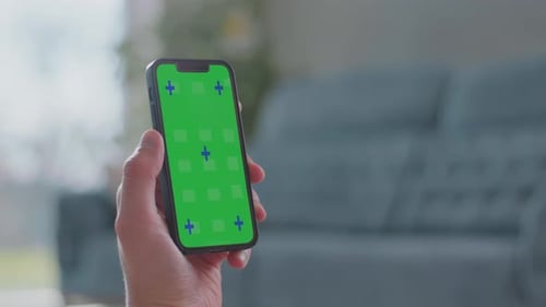 Hand Holding Phone with Green Screen in Home