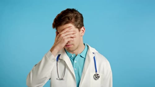 Sad Doctor Covering Face with Hand in Studio