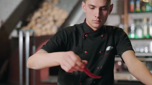 Man Putting Red Chili Pepper on Top of Pizza Dough