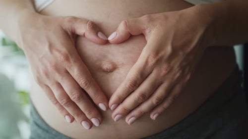 Close up video of heart made of hands on abdomen. Shot with RED helium camera in 8K