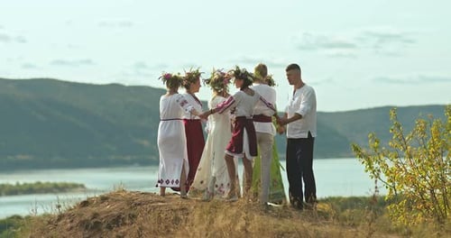 Group of Young People in Slavic Folk Costumes Lead a Round Dance on the Mountain