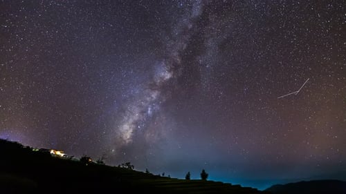 Time lapse of Milky Way Galaxy over hut on paddy rice field at night sky.