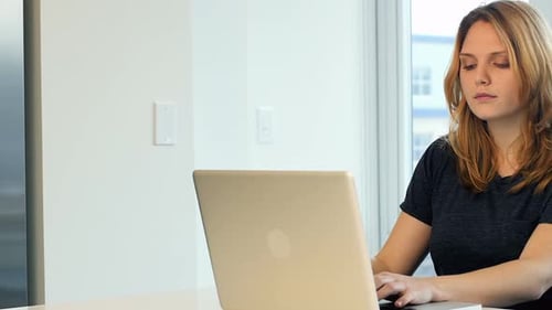 Woman Typing on Laptop at Desk in Home