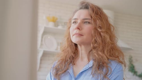 Woman with Curly Hair Looks Thoughtful Indoors