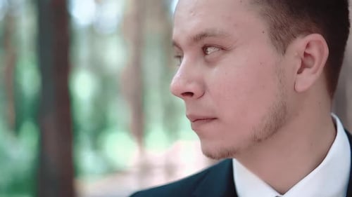 Portrait de jeune homme debout parmi les arbres et regardant au loin