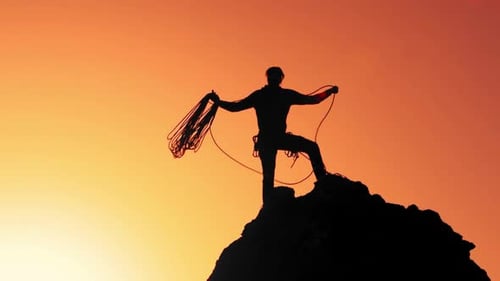A Climber On Top Of The Rock Prepares The Rope