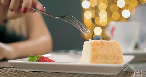 Woman eats delicious slice of cake with fork