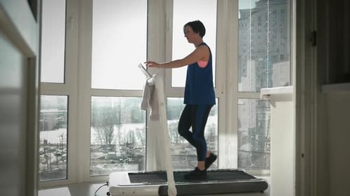 Woman Walking on Treadmill in Bright Apartment