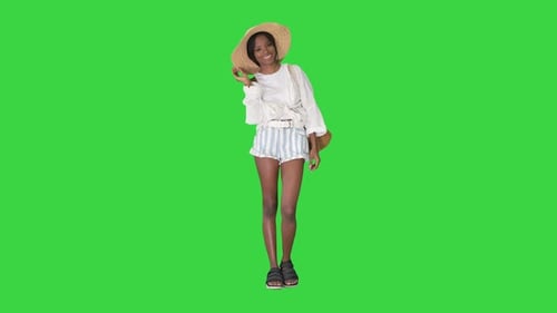Smiling Young African American Woman in a Straw Hat Posing on a Green Screen, Chroma Key.