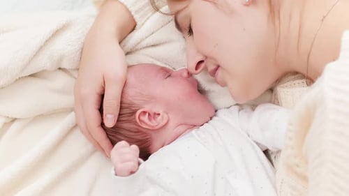 Mother Soothes Newborn Baby With Gentle Touch
