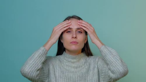Close up of woman doing facial massage isolated on mint.