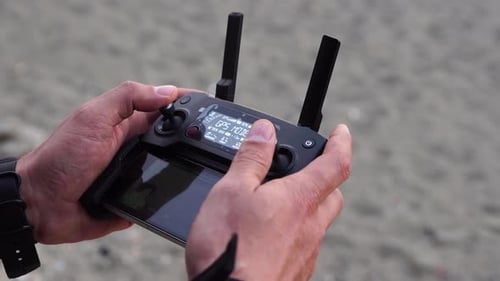 Man Using Drone Controller on Beach