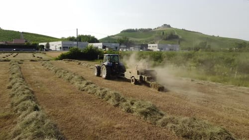 Traktormaschine arbeitet an Heuballen im Weizenfeld