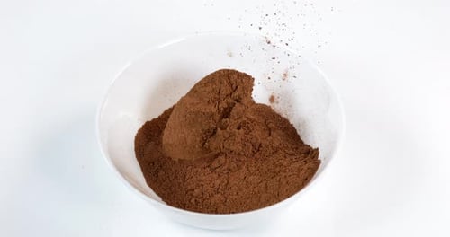Brown Powder Being Poured into White Bowl