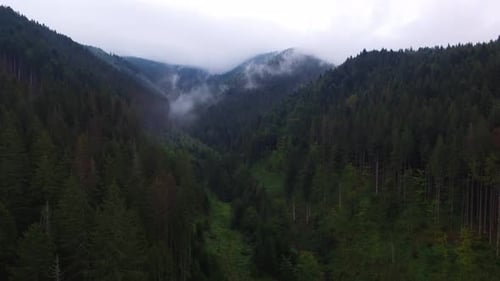 Aerial View. Flying over the high mountains in beautiful clouds. Aerial camera shot.