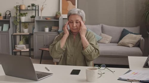 Woman Massaging Temples at Her Desk