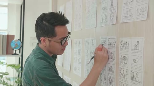Asian Man Drawing Storyboard Animation Comic Cartoon, Design Creative Scene Layout At Studio
