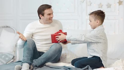 Son Giving Father Birthday Present on Bed