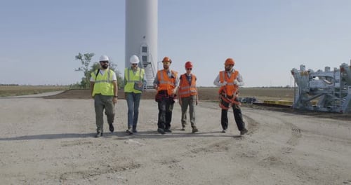 Group of Engineers Walking and Talking on Wind Farm