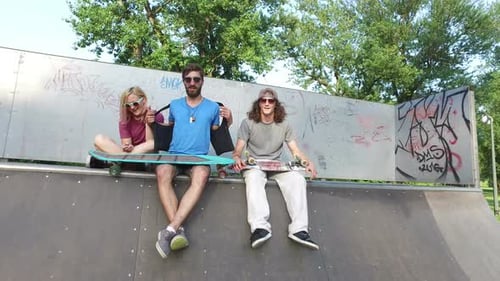 Friends sitting on a ramp at skatepark and chilling