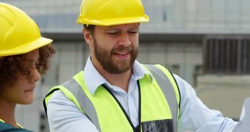 Construction Workers Reviewing Blueprints on Site