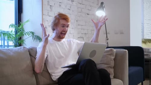 Excited Man Working on Laptop at Home