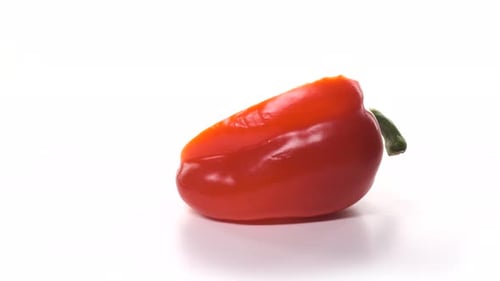 Un pimiento rojo medio recién cortado gira sobre fondo blanco