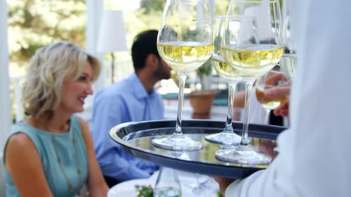 Waiter Brings Wine to People at Outdoor Table