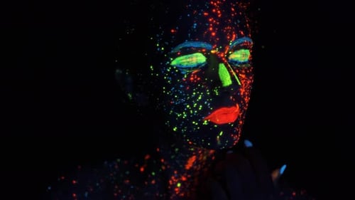 Neon Paint on the Face. Portrait of a Girl Painted with Glowing Paint