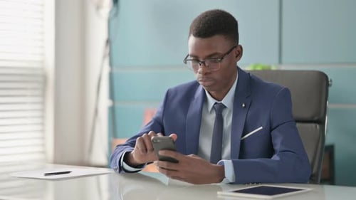 Joven empresario africano con smartphone en la oficina