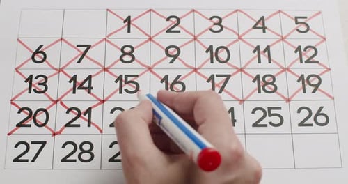 Man's Hand escribe el día 2122232425 en el calendario con un bolígrafo rojo