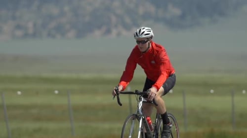 A man road biking on a scenic road.