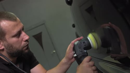 Man Polishing Car with Power Buffer in Garage