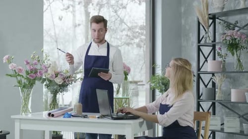 Young Happy Woman Works at Laptop Together with Male Florist Uses an Online Service To Accepting