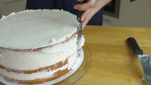 Close up of woman hands making sweet cake with white cream and biscuit.